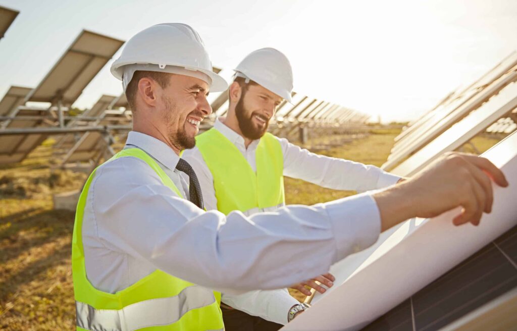 Men in construction gear smiling looking at solar panels.