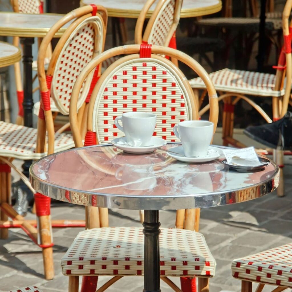 An outside cafe table with cups and saucers.